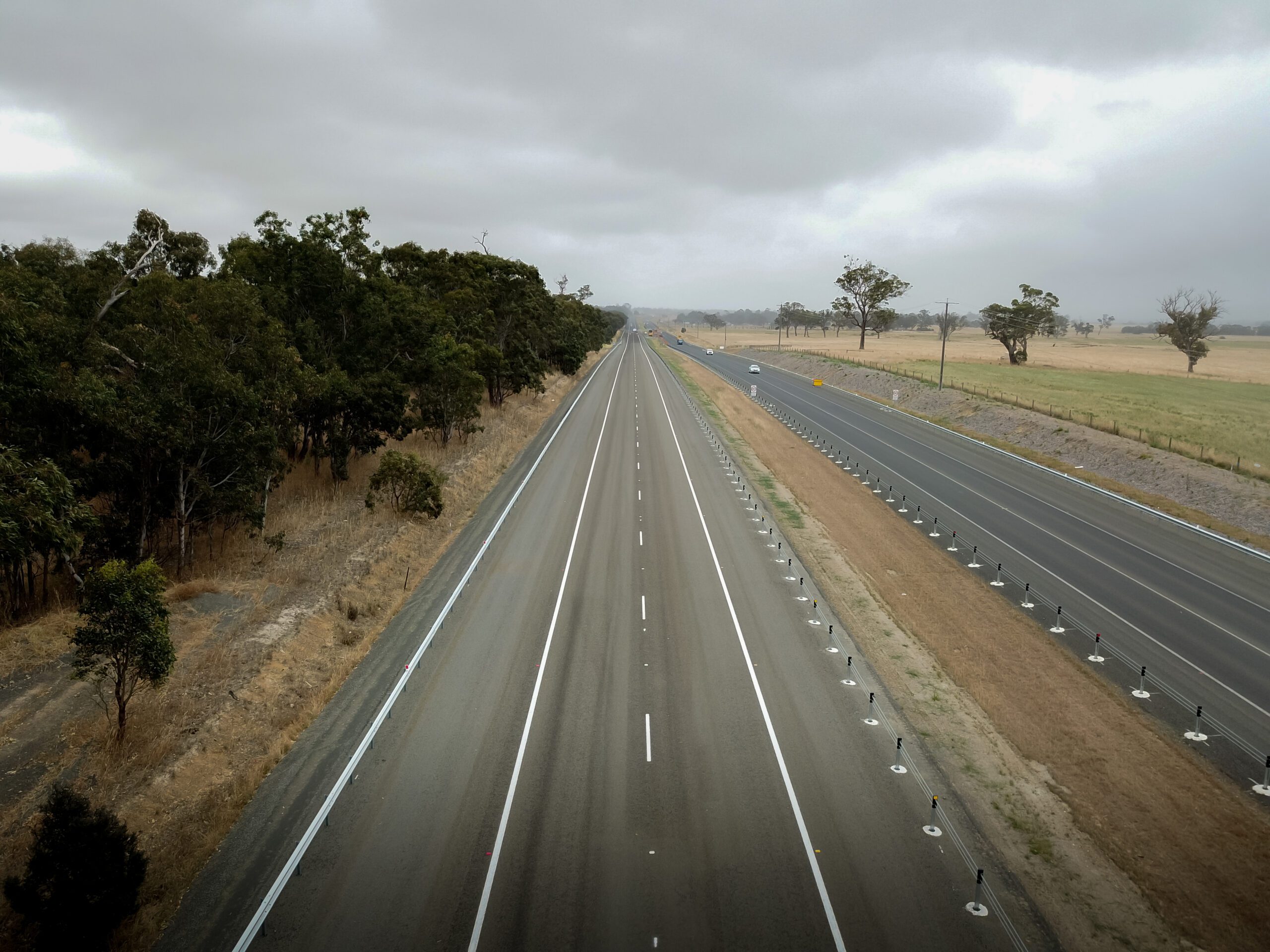 Aerial view of VicRoads Princes Highway with multiple lanes, roadside trees and farmland