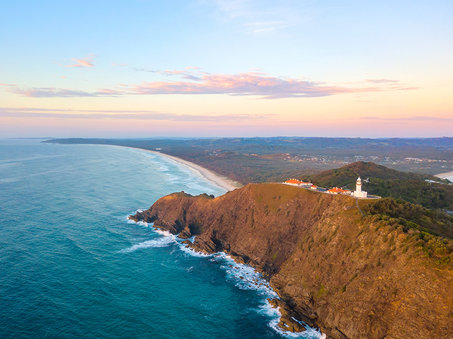 Aerial view of Byron Bay coastline with Cape Byron Lighthouse, blue ocean and sandy beach