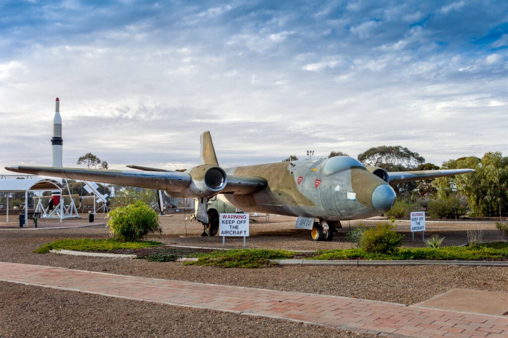 Preserved military aircraft display at Woomera with missile exhibit and warning signs nearby