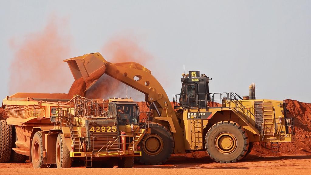 Large wheel loader loading red earth into a mining haul truck at an open-cut mine site