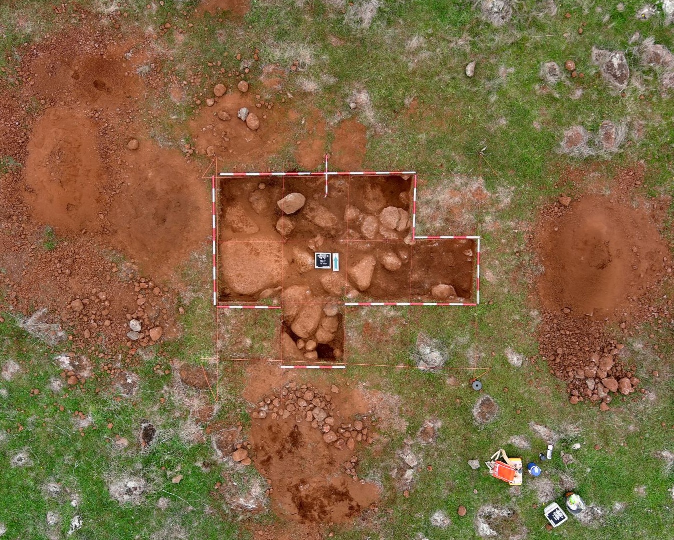 Aerial view of ACHM archaeological site monitoring with excavation grids, exposed rocks and red soil