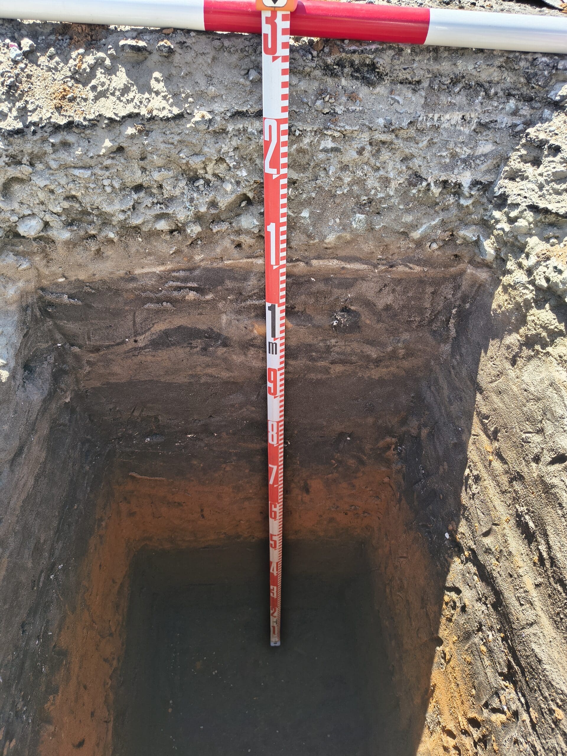 ACHM archaeological test pit profile showing stratigraphic soil layers and measured excavation depth